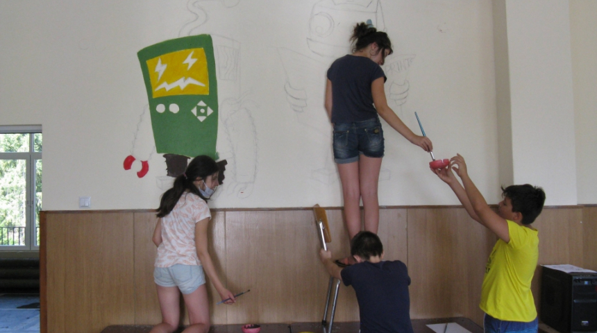 Учител и малките му художници рисуват по училищни стени